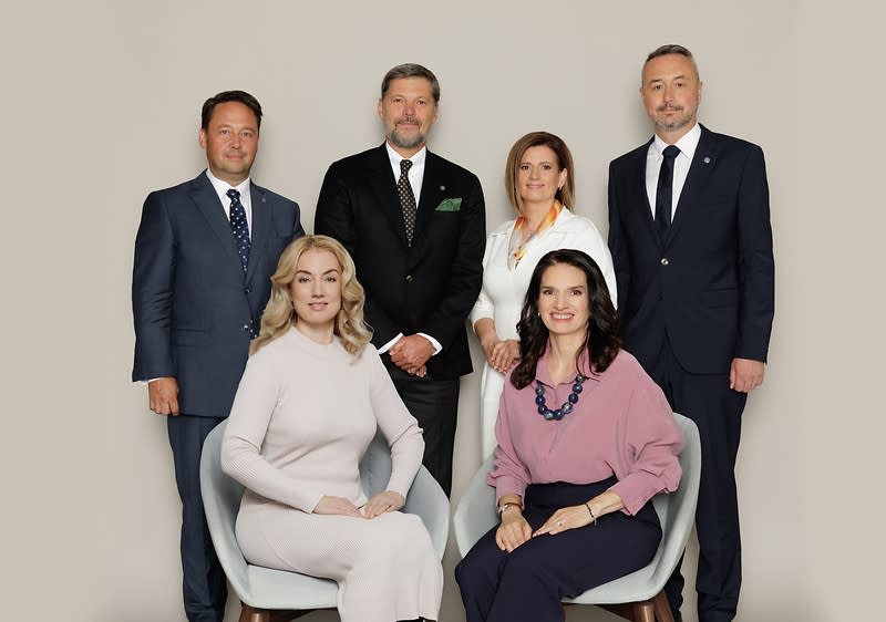 Grup de oameni în ținute formale, două persoane așezate și patru în picioare