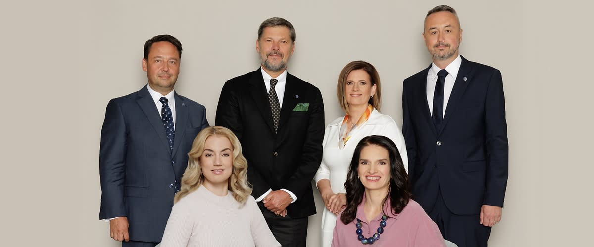 Grup de oameni în ținute formale, două persoane așezate și patru în picioare