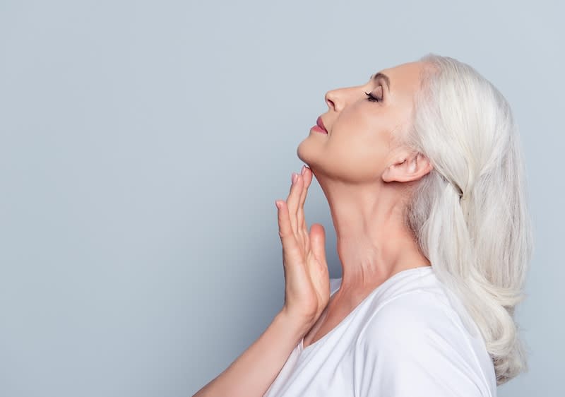 Ältere Frau streicht sich über den Hals