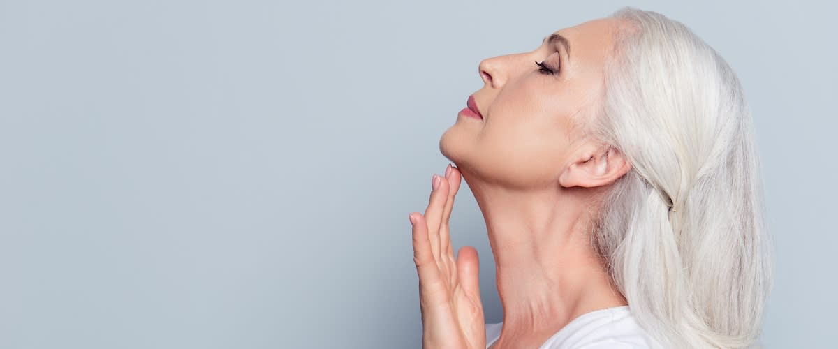 Ältere Frau streicht sich über den Hals