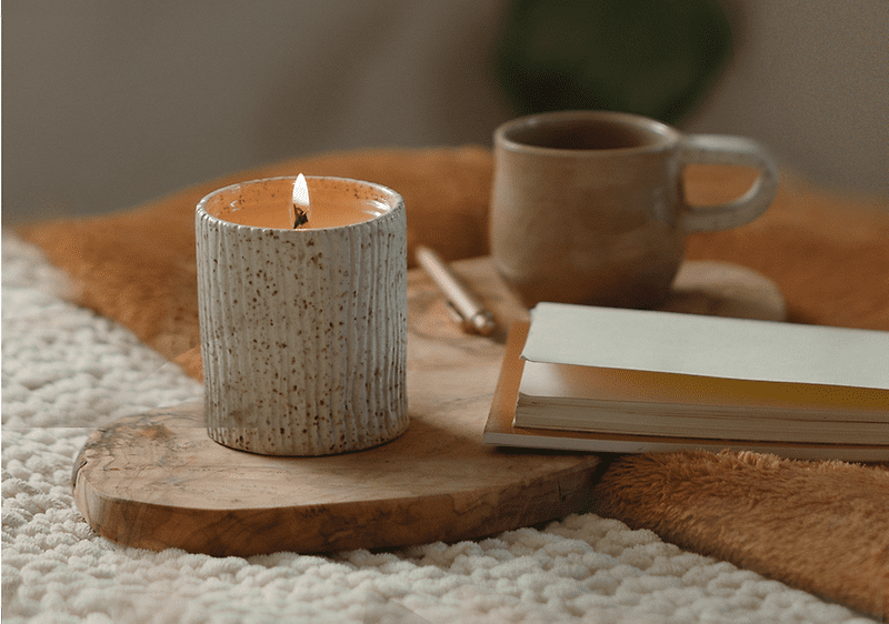 Buch, Kerze und Tasse liegen auf dem Bett