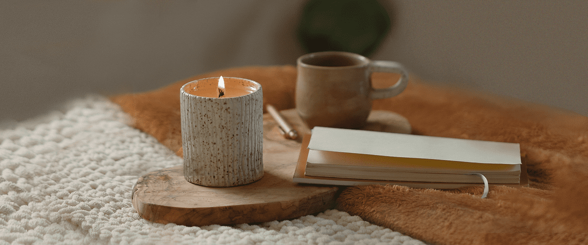 Buch, Kerze und Tasse liegen auf dem Bett