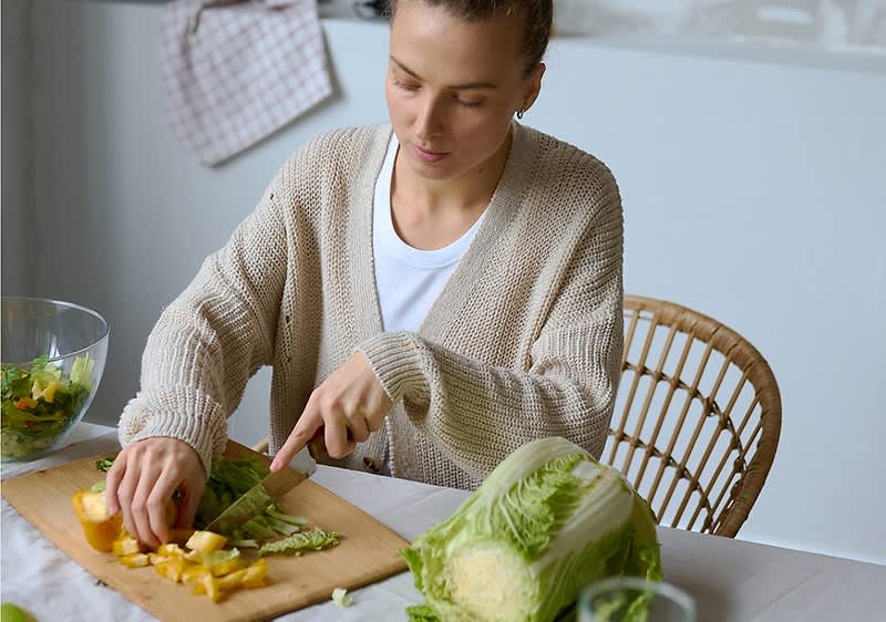 Frau beim Gemüse schneiden