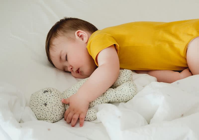 Baby schläft neben Teddybär