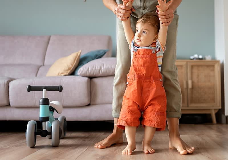 Baby steht aufrecht mit Papas Hilfe