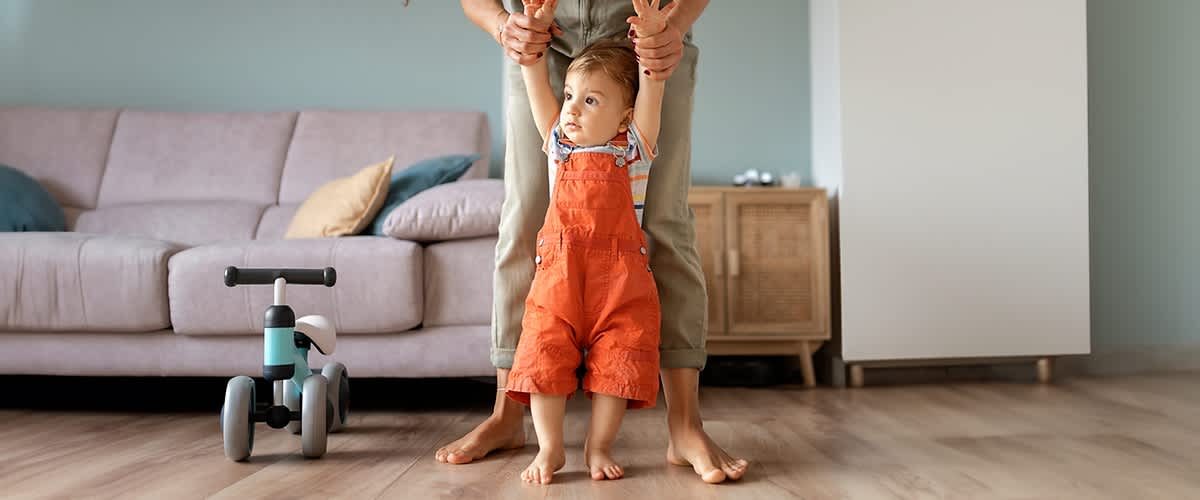 Baby steht aufrecht mit Papas Hilfe