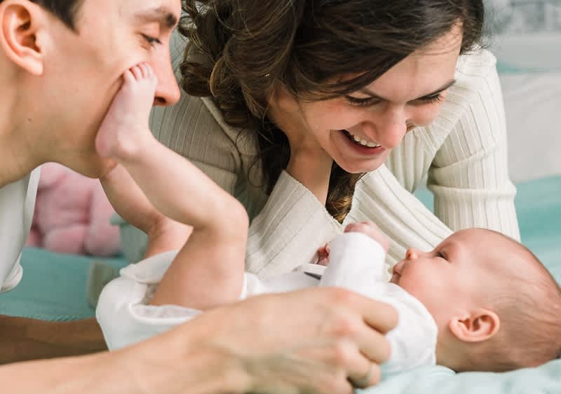 Vater und Mutter lächeln neugeborenes Baby an