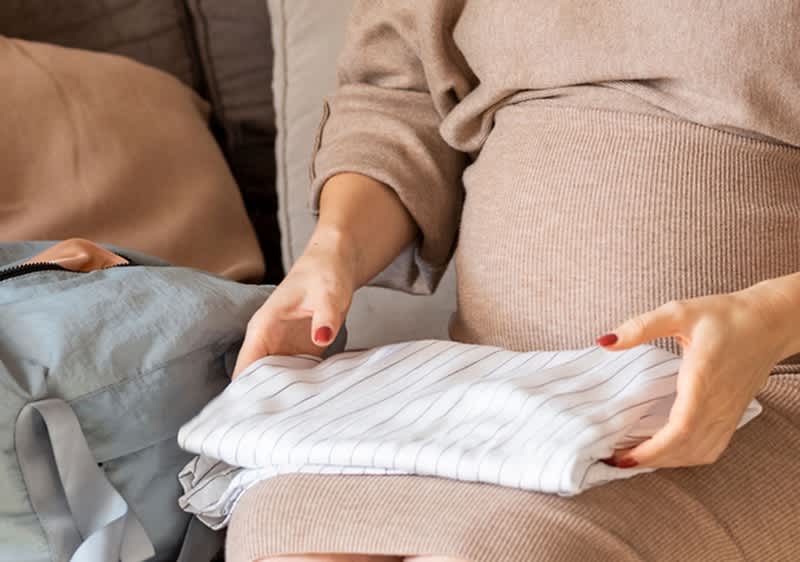 Schwangere Frau packt Kliniktasche