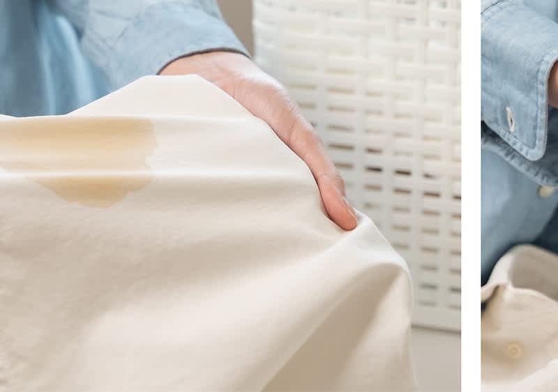 Cămașă albă cu pată de cafea ținută de o mână