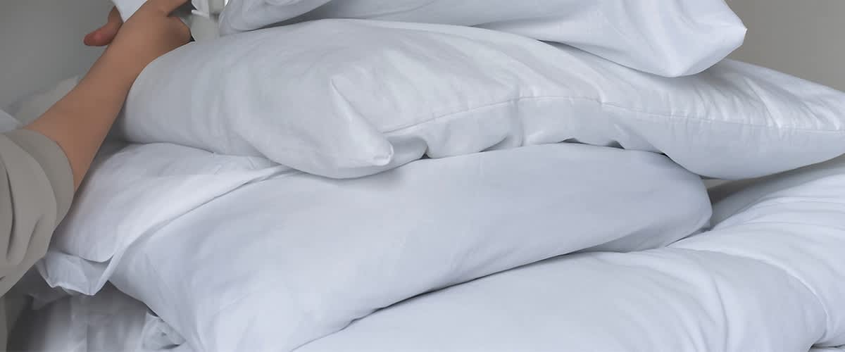 Pernă albă și plapumă albă pe pat