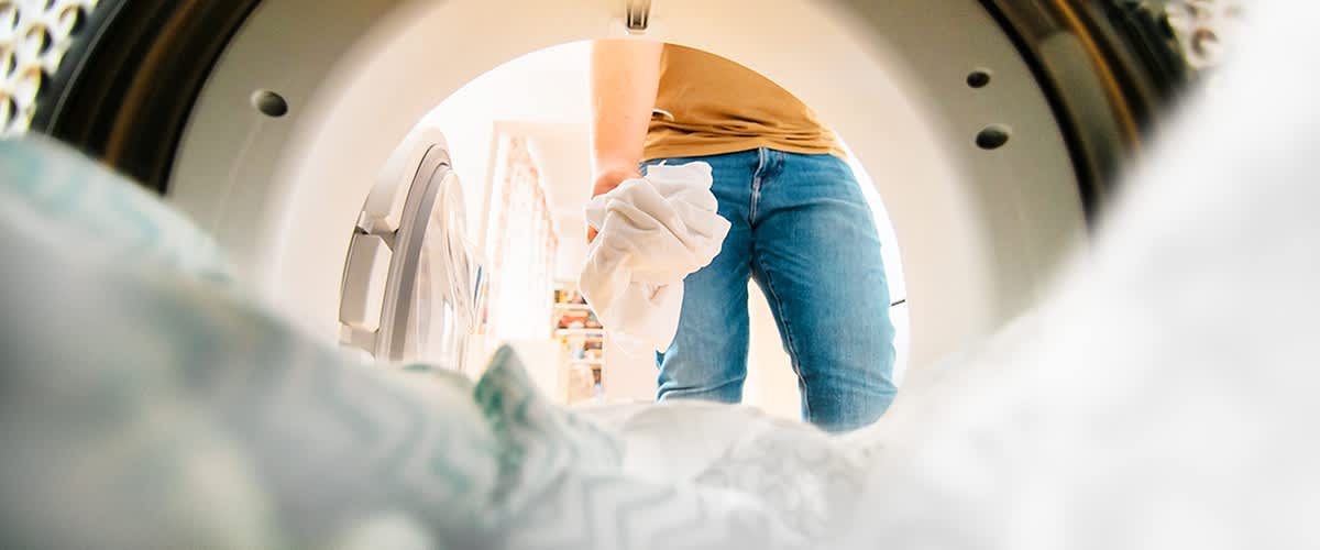 Persoană punând haine în mașina de spălat