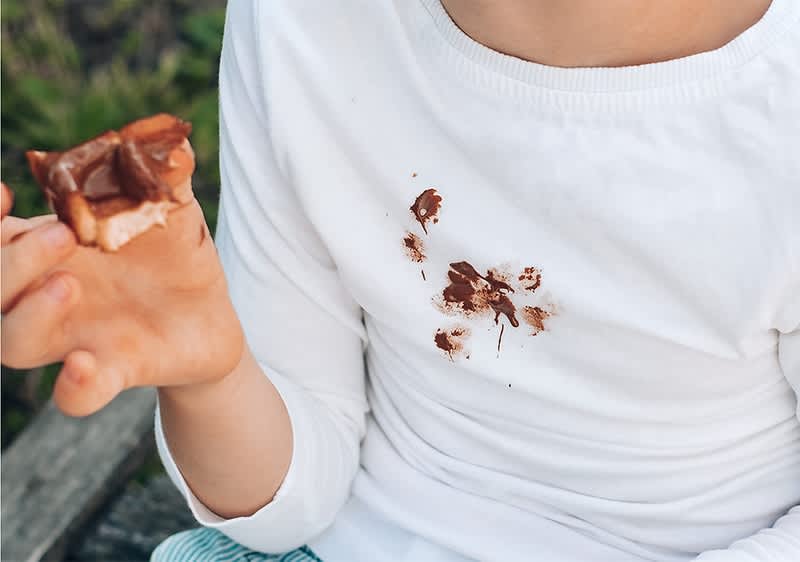 Copil cu tricou alb pătat de ciocolată