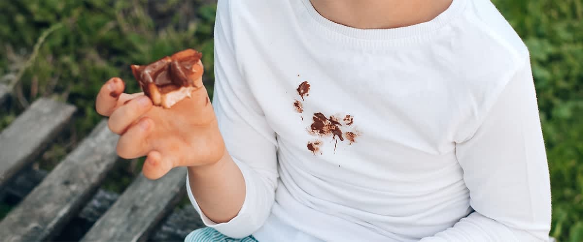 Copil cu tricou alb pătat de ciocolată