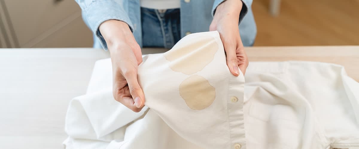 Cămașă albă cu pete de cafea ținută în mâini