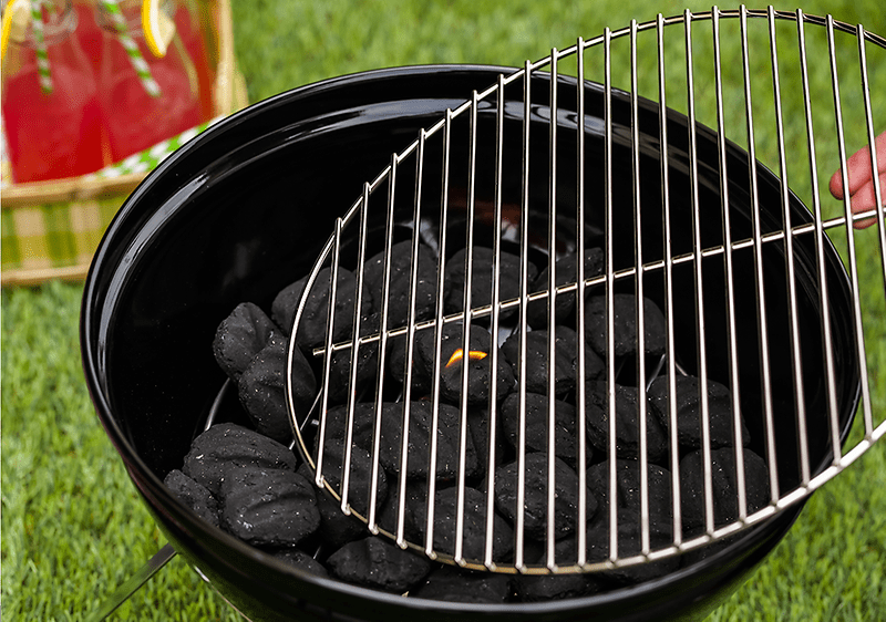 Grătar cu cărbuni aprinși pe iarbă