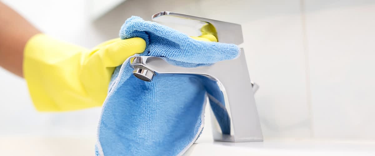 Curățare robinet cu cârpă albastră și mănușă galbenă