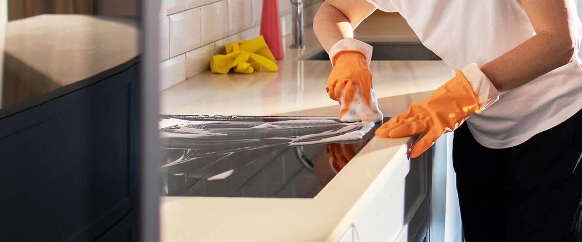 Curățare aragaz cu mănuși portocalii și detergent