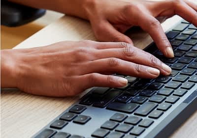 Mâini tastând pe o tastatură de computer
