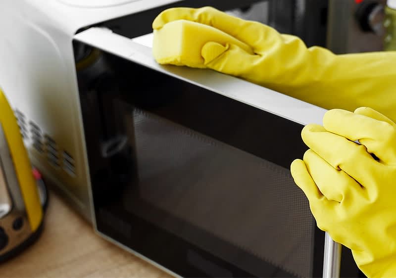 Curățare cuptor cu microunde cu mănuși galbene
