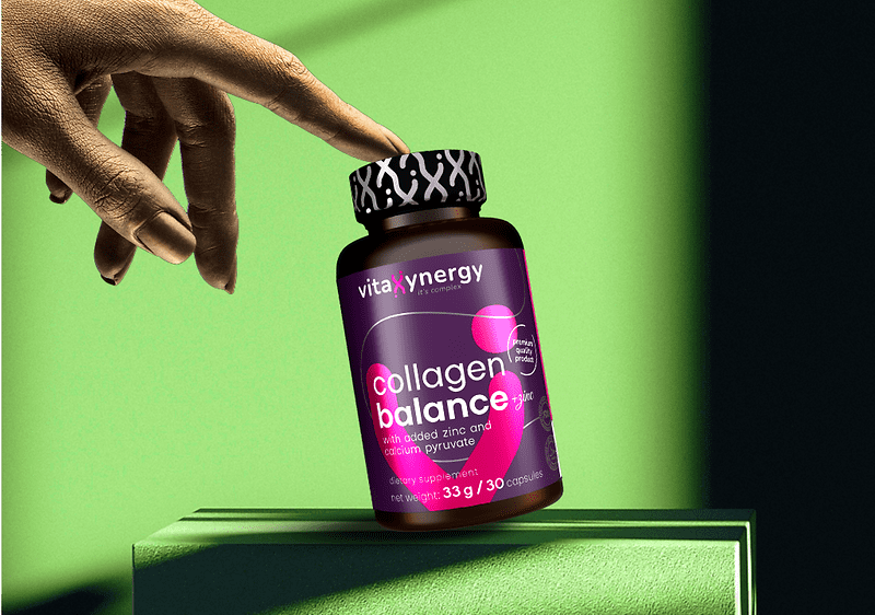 Mână atingând sticla de supliment collagen balance pe fundal verde