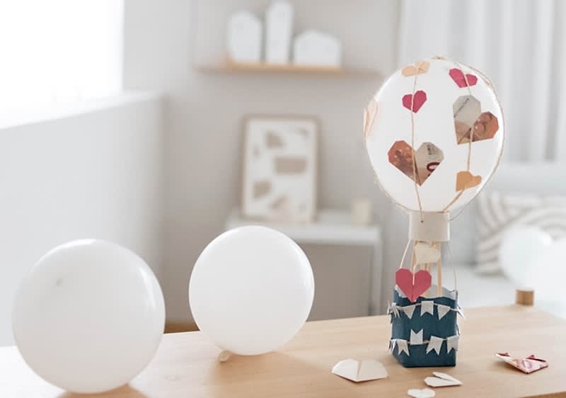 Decor balon cu inimioare într-o cameră luminoasă cu baloane albe pe masă
