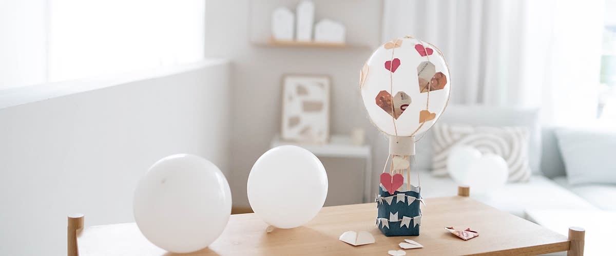 Decor balon cu inimioare într-o cameră luminoasă cu baloane albe pe masă