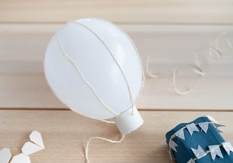 Decor balon alb cu sfoară pe masă de lemn și cutie albastră decorată cu stele argintii