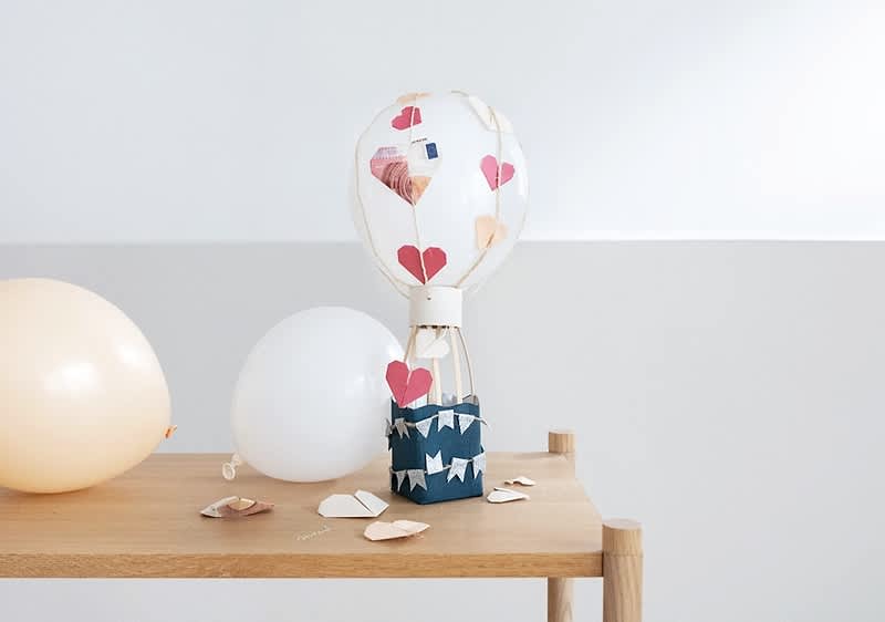 Balon decorativ cu inimioare pe masă de lemn și baloane albe și crem