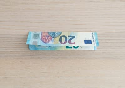 Bancnotă de 20 euro împăturită pe masă de lemn