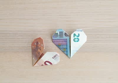 Bancnote euro pliate în formă de inimă pe fundal de lemn