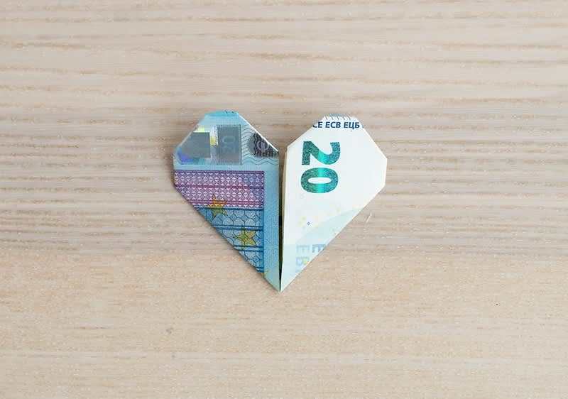 Origami inimă realizată dintr-o bancnotă de 20 de euro pe masă de lemn