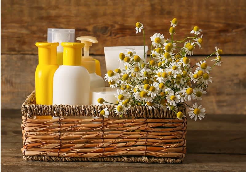 Produse cosmetice și flori de mușețel într-un coș de răchită