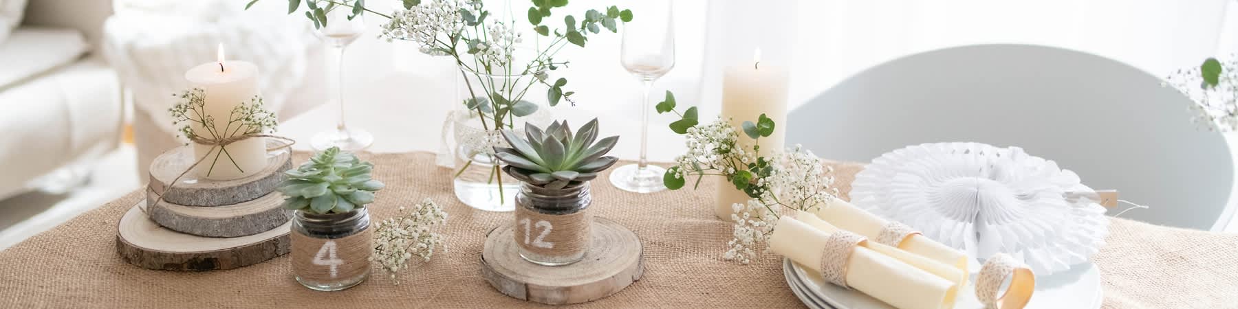 Decor de masă rustic cu plantă suculentă, lumânare, flori albe și pahar de vin