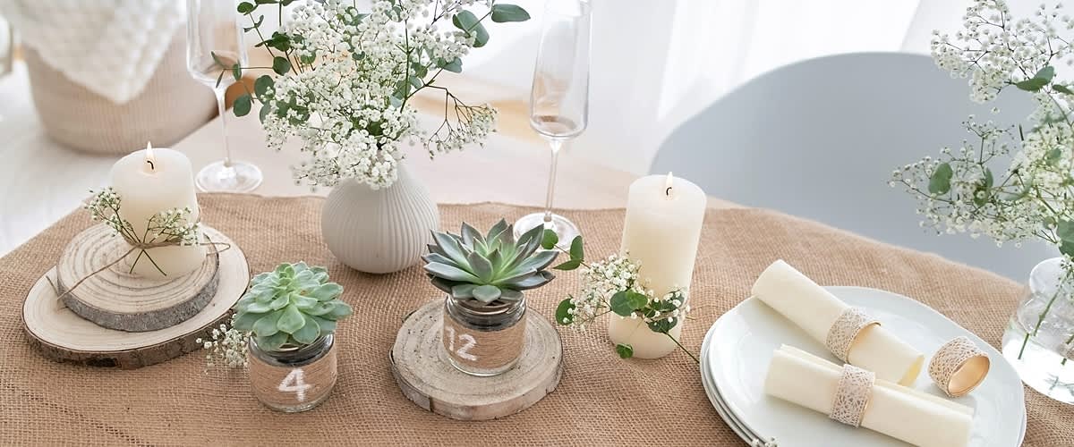 Decor de masă cu plante suculente, flori albe, lumânare și farfurii elegante