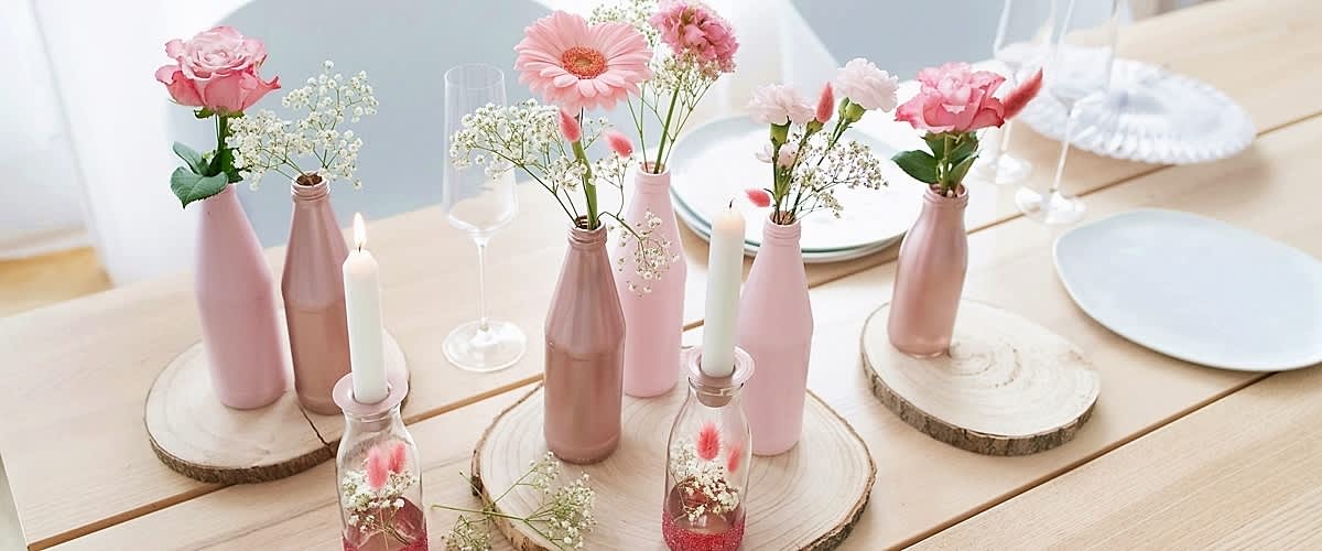 Decor floral cu flori roz în sticle roz și lumânări pe suporturi de lemn