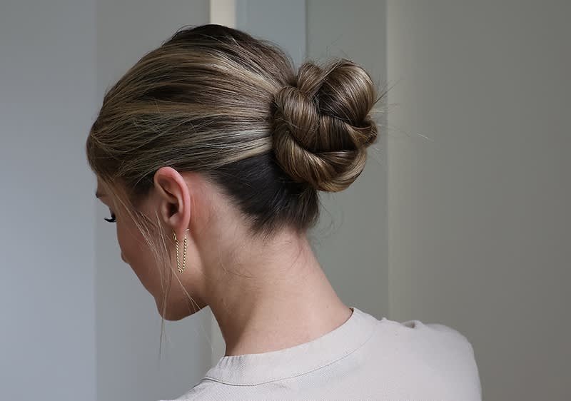 Persoană cu coc elegant și păr blond în oglindă