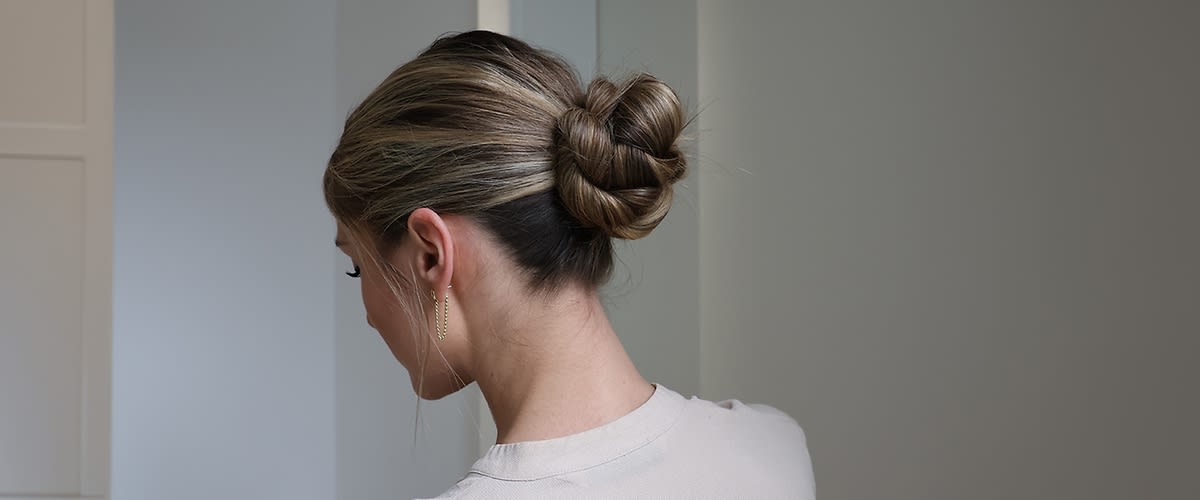 Persoană cu coc elegant și păr blond în oglindă