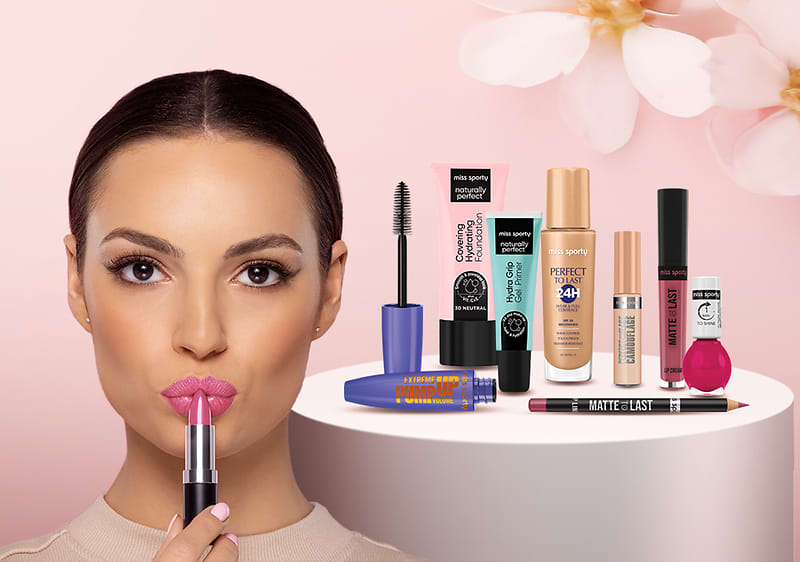 Produse cosmetice diverse pe un suport alb cu fundal roz și flori albe