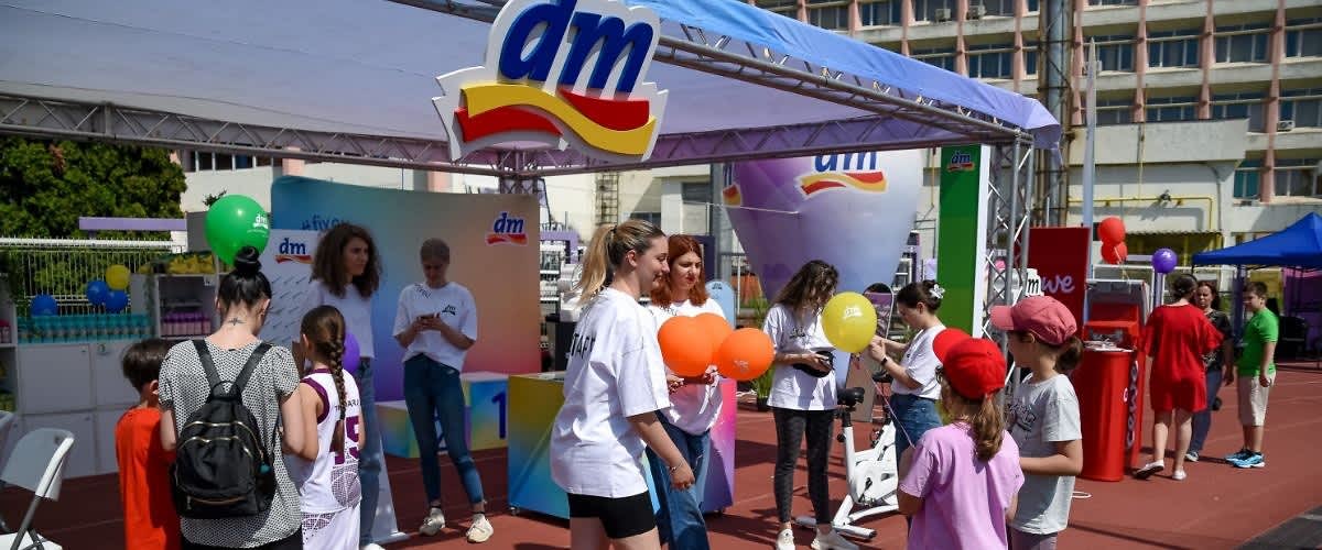 Oameni la un eveniment promoțional DM cu baloane și standuri