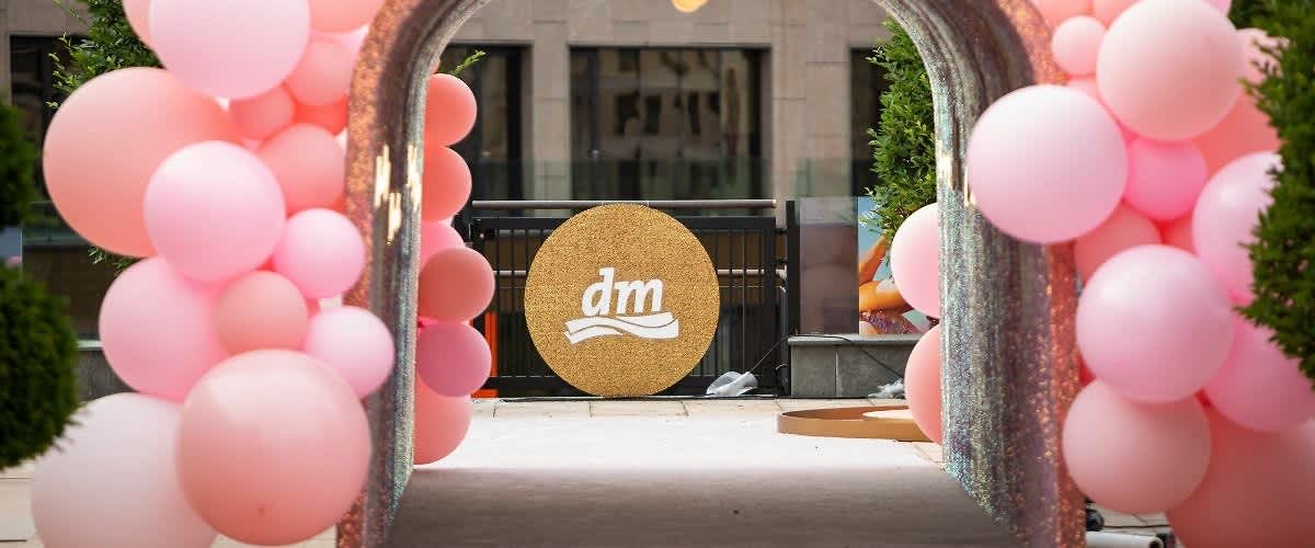 Arcadă decorată cu baloane roz și logo dm pe fundal