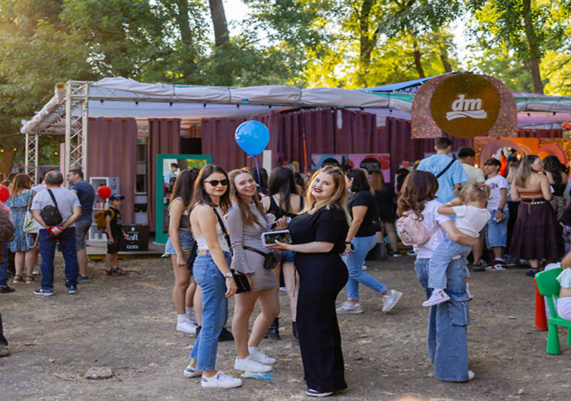 Grup de oameni la un festival în aer liber cu standuri și balon albastru