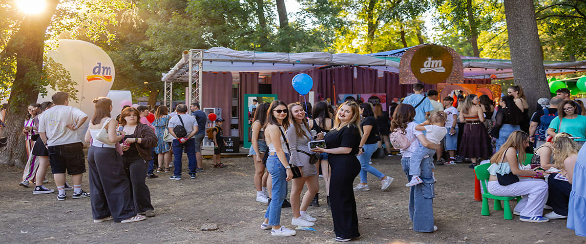 Grup de oameni la un festival în aer liber cu standuri și balon albastru