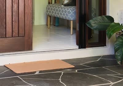 Covoraș de ușă pe terasă cu ușă deschisă și plantă în ghiveci