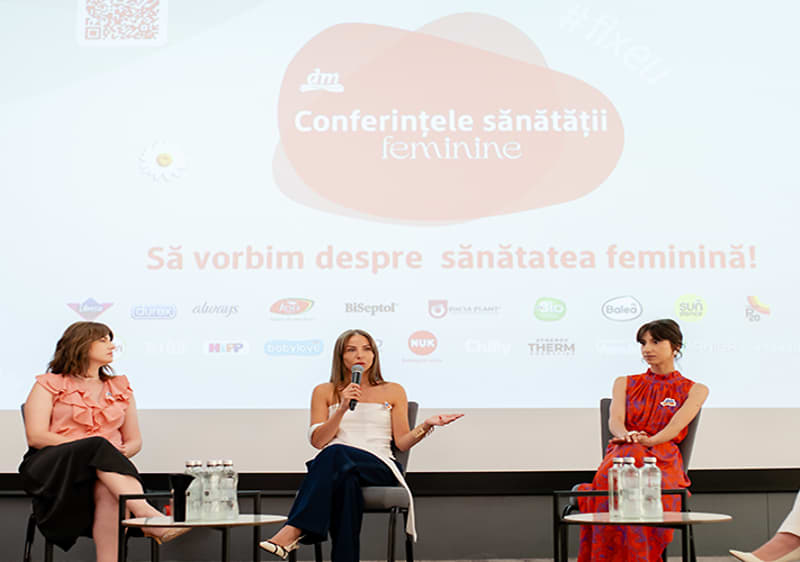 Conferință despre sănătatea feminină cu trei femei pe scenă discutând