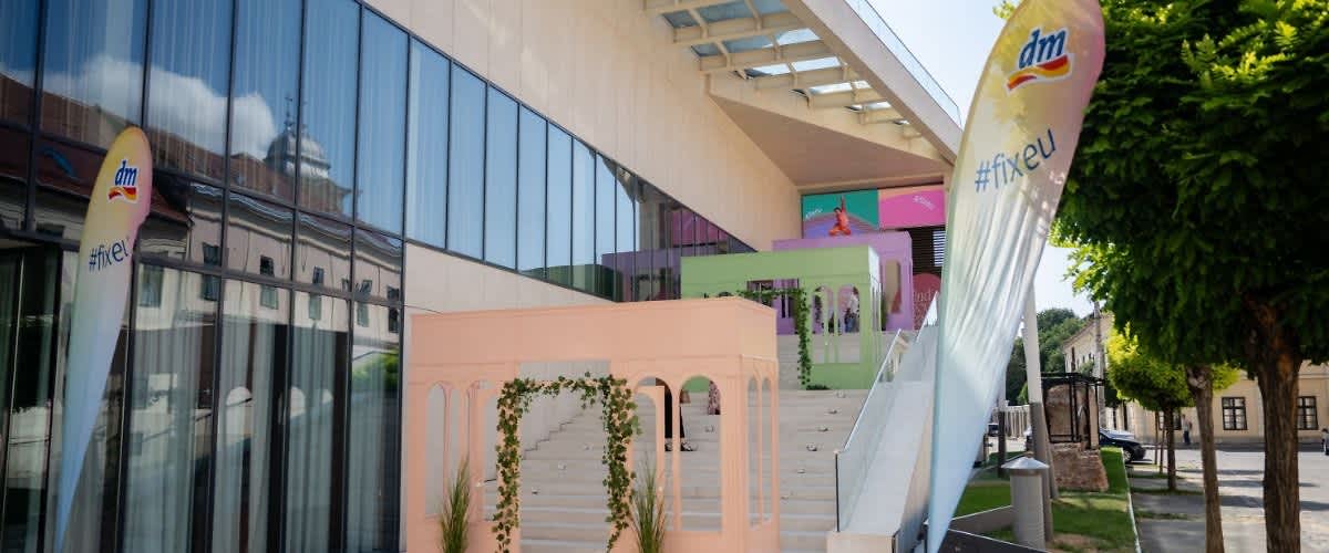 expoziție Expoziție colorată pe scări exterioare cu structuri pastelate și banner DM