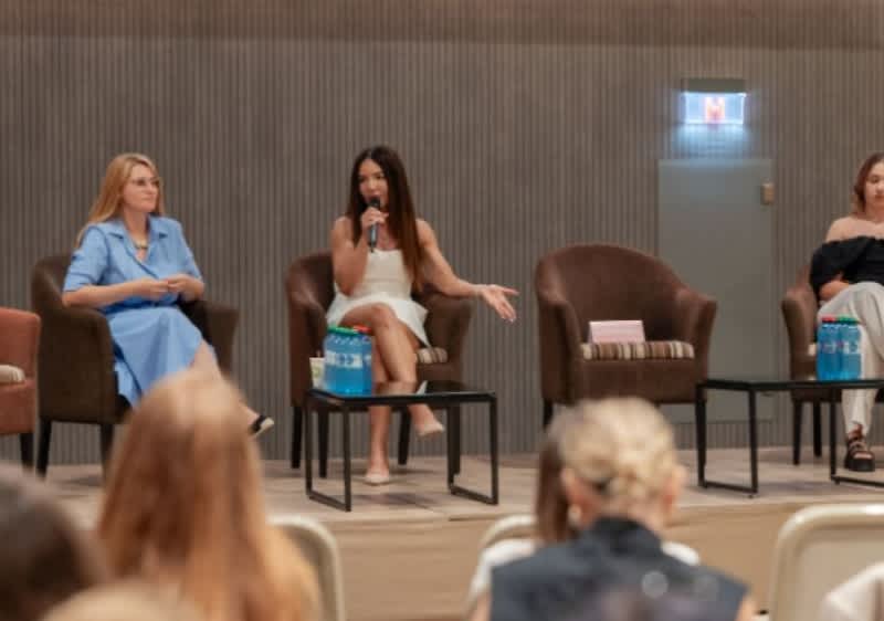 Panel de discuție cu trei femei pe scenă în fața unui public