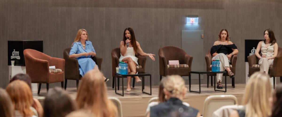 Panel de discuție cu trei femei pe scenă în fața unui public