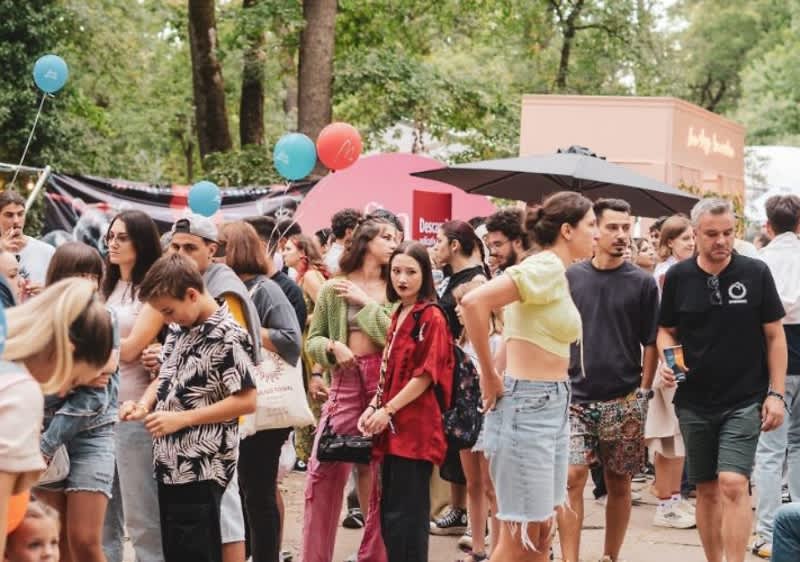 O mulțime de oameni la un festival în aer liber cu baloane și copaci