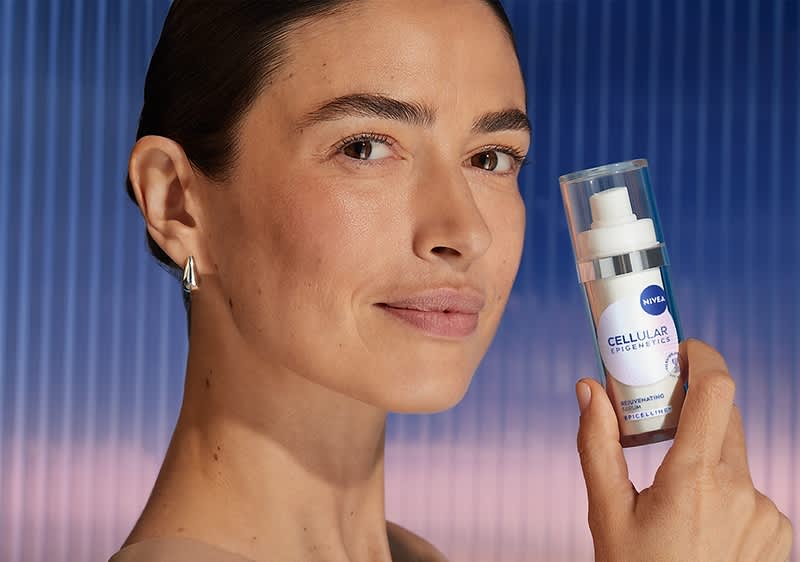 Cremă anti-îmbătrânire Nivea ținută de o persoană cu cer albastru în fundal