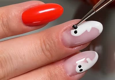 Unghii cu design de Halloween, o unghie roșie și două unghii cu fantome albe și ochi negri